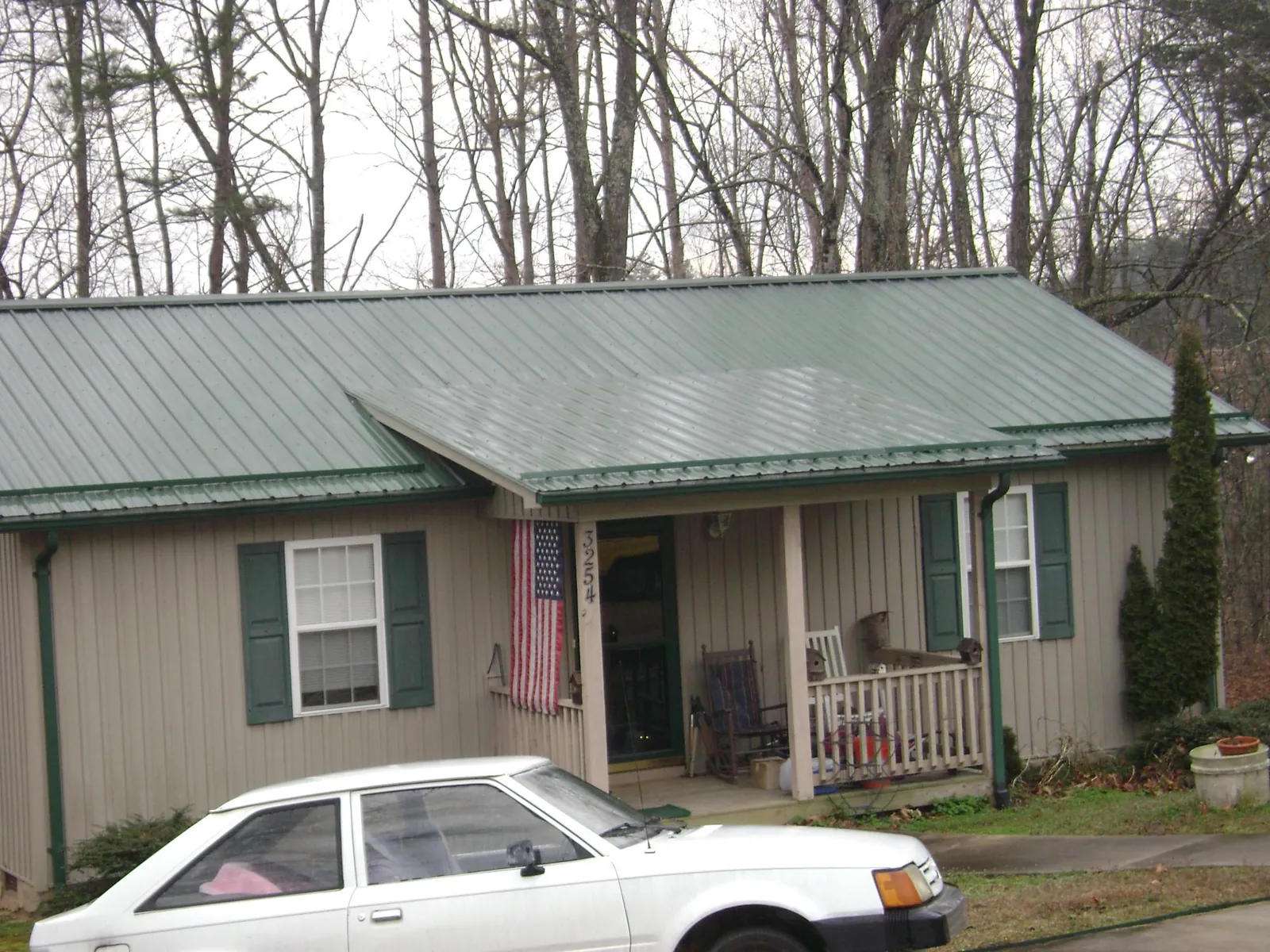 Green metal roof and front porch on a tan sided cottage in Jamaica